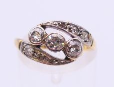 An 18 ct gold and platinum three-stone diamond crossover ring. Ring size L/M.