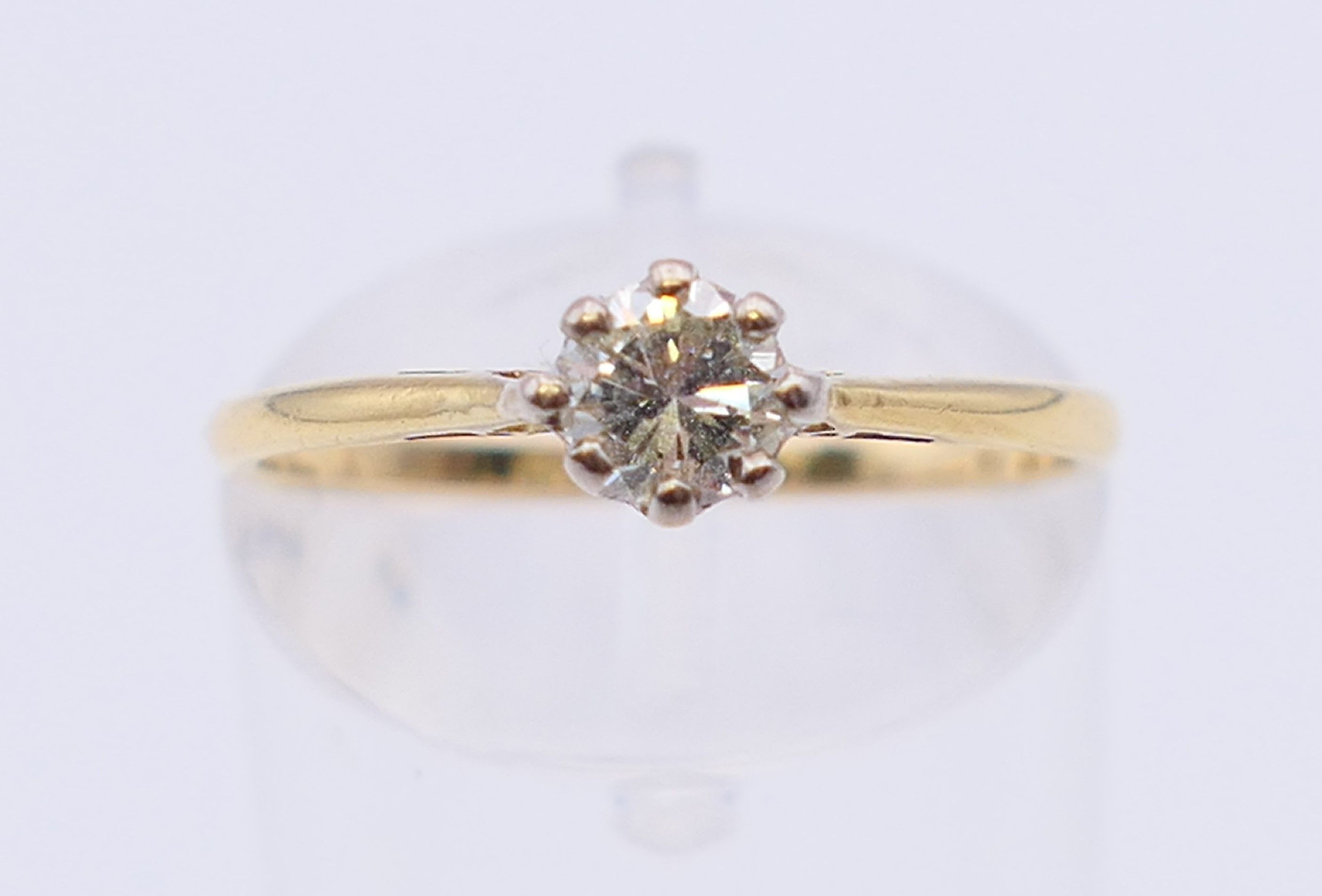 An 18 ct gold and platinum diamond solitaire ring. The claw set stone spreading to 0.25 carat.