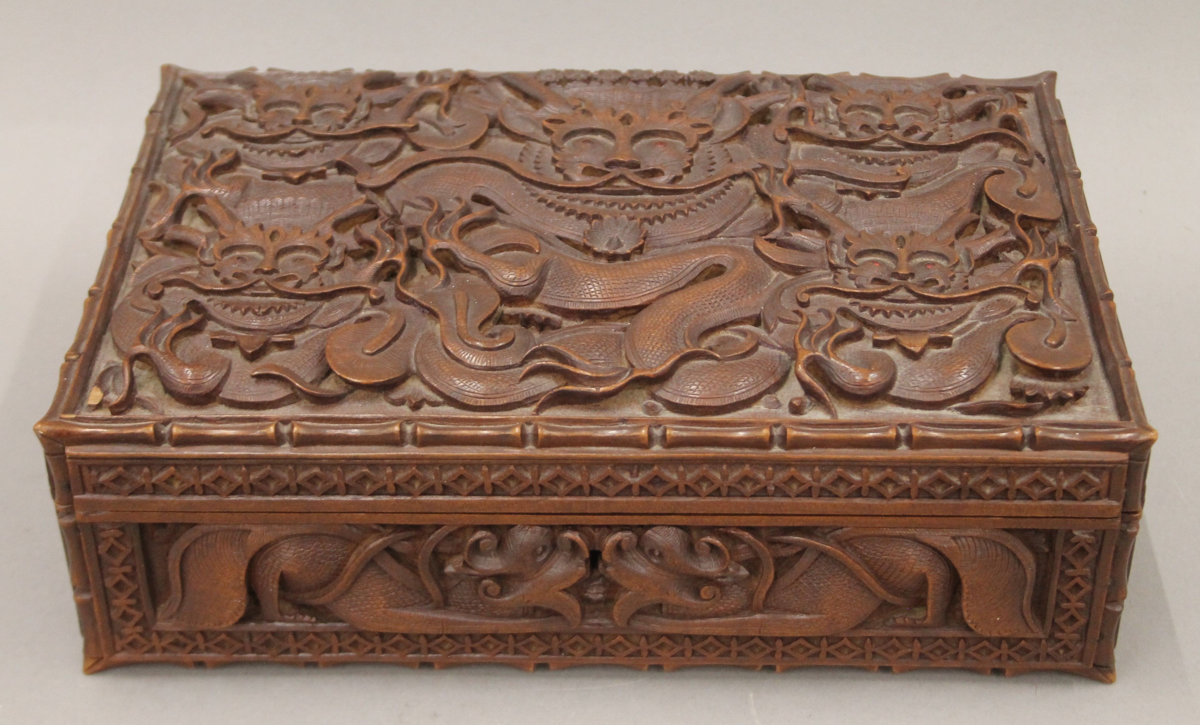 An Eastern carved hardwood box with all-over carved dragon decoration. 30 cm wide.