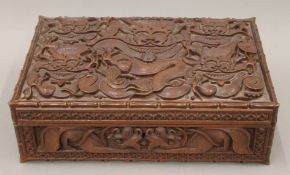 An Eastern carved hardwood box with all-over carved dragon decoration. 30 cm wide.