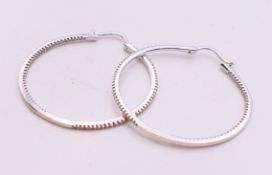 A pair of 14 K white gold diamond hoop earrings. 3.5 cm diameter.