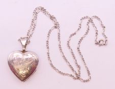 A silver hinged heart shaped locket and chain, the former 2.5 cm high.