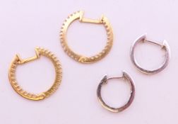 Two pairs of unmarked diamond set earrings, the largest 1.5 cm diameter.