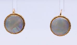 A pair of 9 ct gold and opal earrings. Each 1 cm diameter.