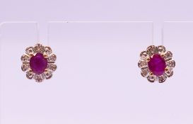 A pair of ruby and diamond ear studs, each 9 mm high.