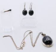 A suite of jet set jewellery to include a pendant on chain, a pair of earrings and a ring.