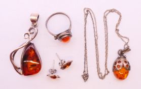 Four silver and amber items of jewellery. The largest pendant 5 cm high.