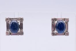 A pair of sapphire and diamond earrings, each of square outline, the oval sapphire cabochon,