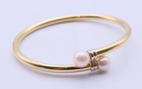 A gold and cultured pearl bangle marked 750. 6.4 cm long, weight 13 grammes.