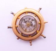 An unmarked gold compass fob formed as a ship's wheel. 2.75 cm diameter. 5 grammes total weight.
