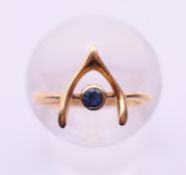 An 18 ct gold and sapphire wishbone ring. Ring size E. 1.7 grammes total weight.