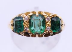 An 18 ct gold emerald and diamond ring. Ring size R.