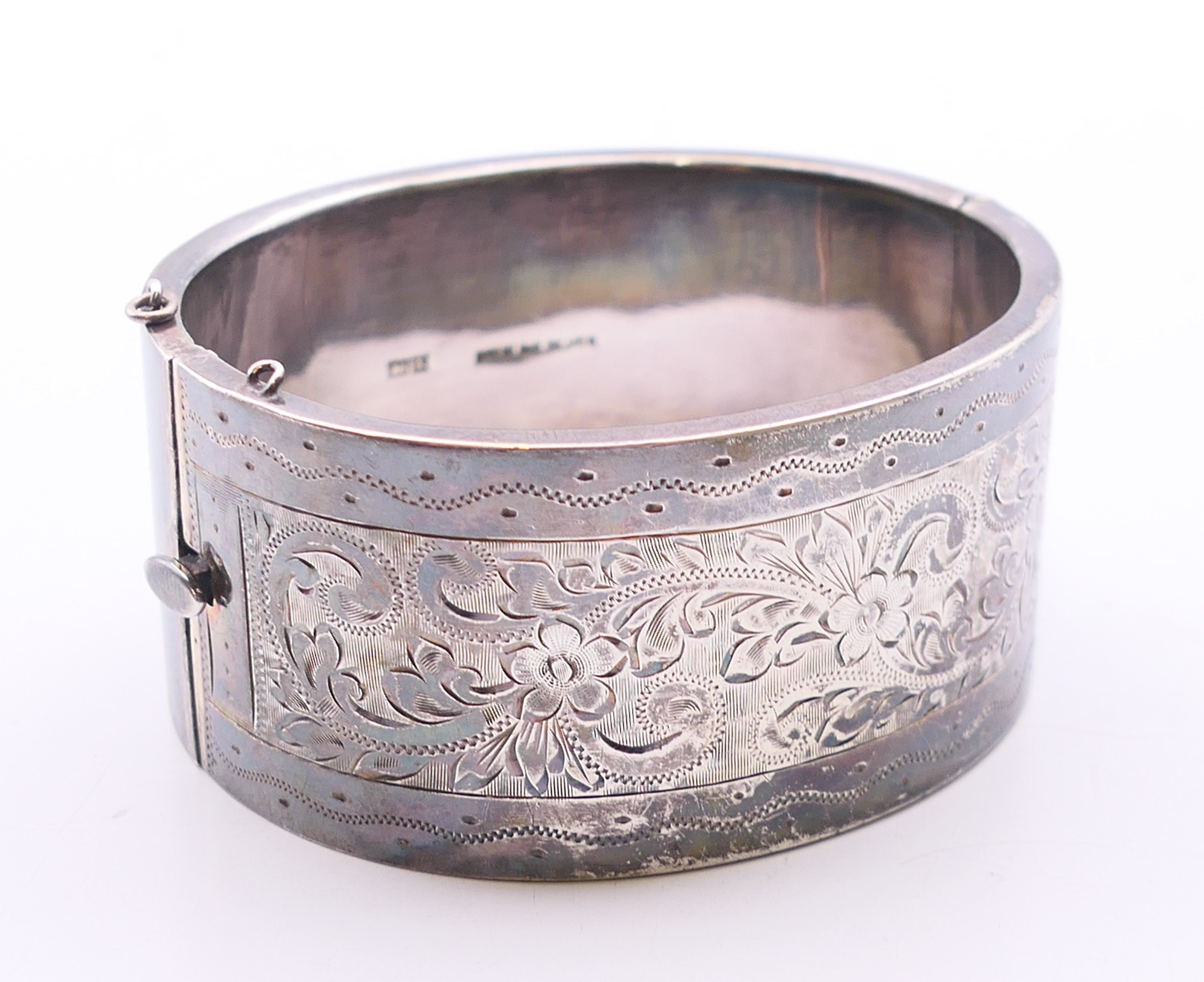 A silver engraved bangle. 6 cm inner diameter. 53.7 grammes.