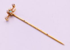 An unmarked gold, diamond and opal stick pin. 6 cm high.