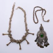 An Ethnic rock crystal necklace, a mixed metal necklace and a pendant. The former 45 cm long.