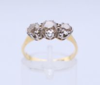 An 18 ct gold and platinum three-stone diamond ring. The central stone spreading to approximately 0.