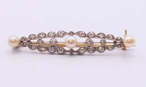 An unmarked gold, diamond and pearl bar brooch. 4.5 cm wide.