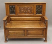 An Arts and Crafts oak box settle. 126.5 cm wide, 110 cm high, 47 cm deep.