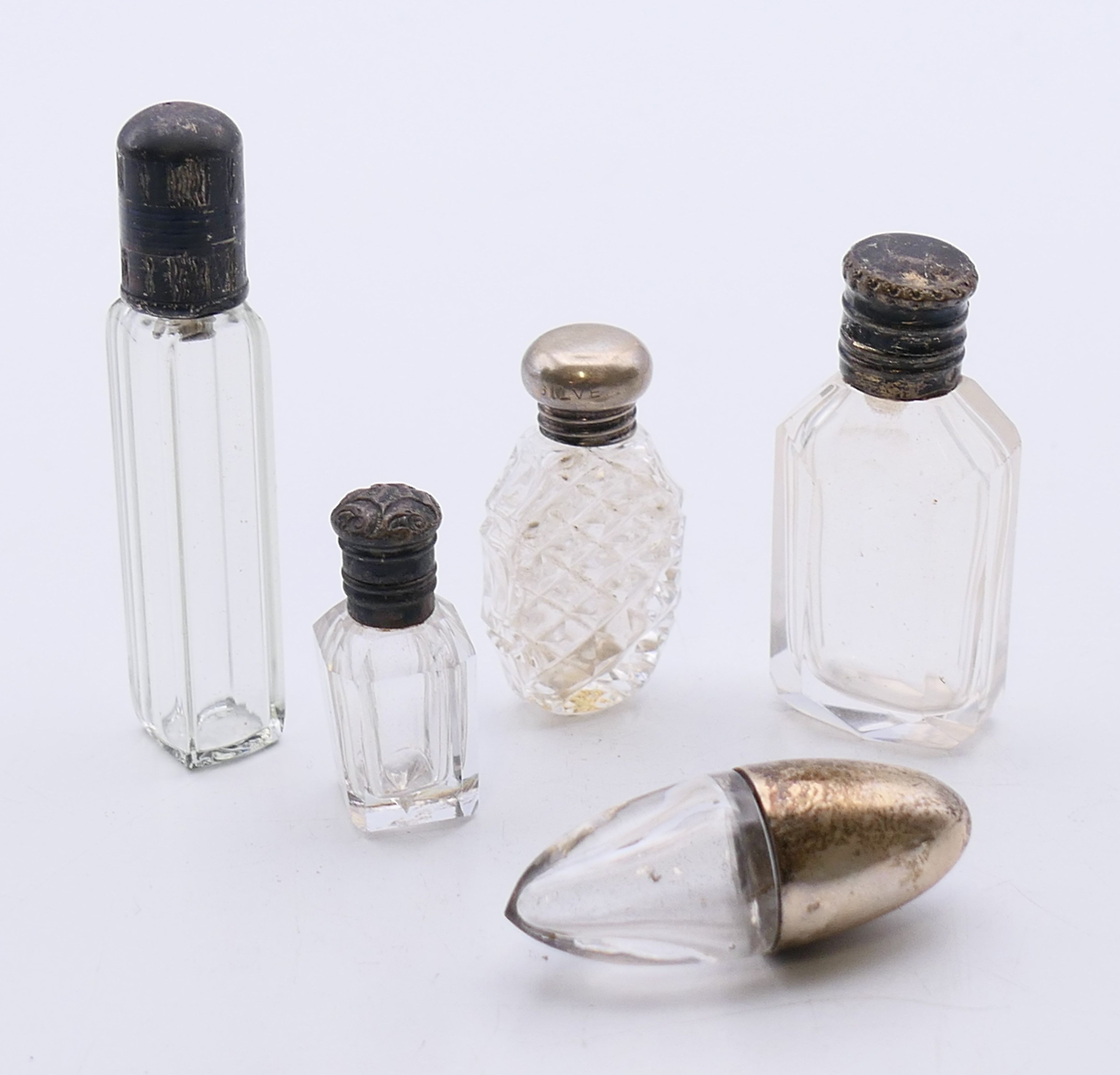 Five mini silver-topped glass scent bottles. The tallest 6.25 cm high.