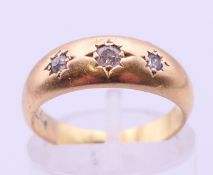 An 18 ct gold three-stone diamond gypsy set ring. 3.1 grammes total weight. Ring size L.