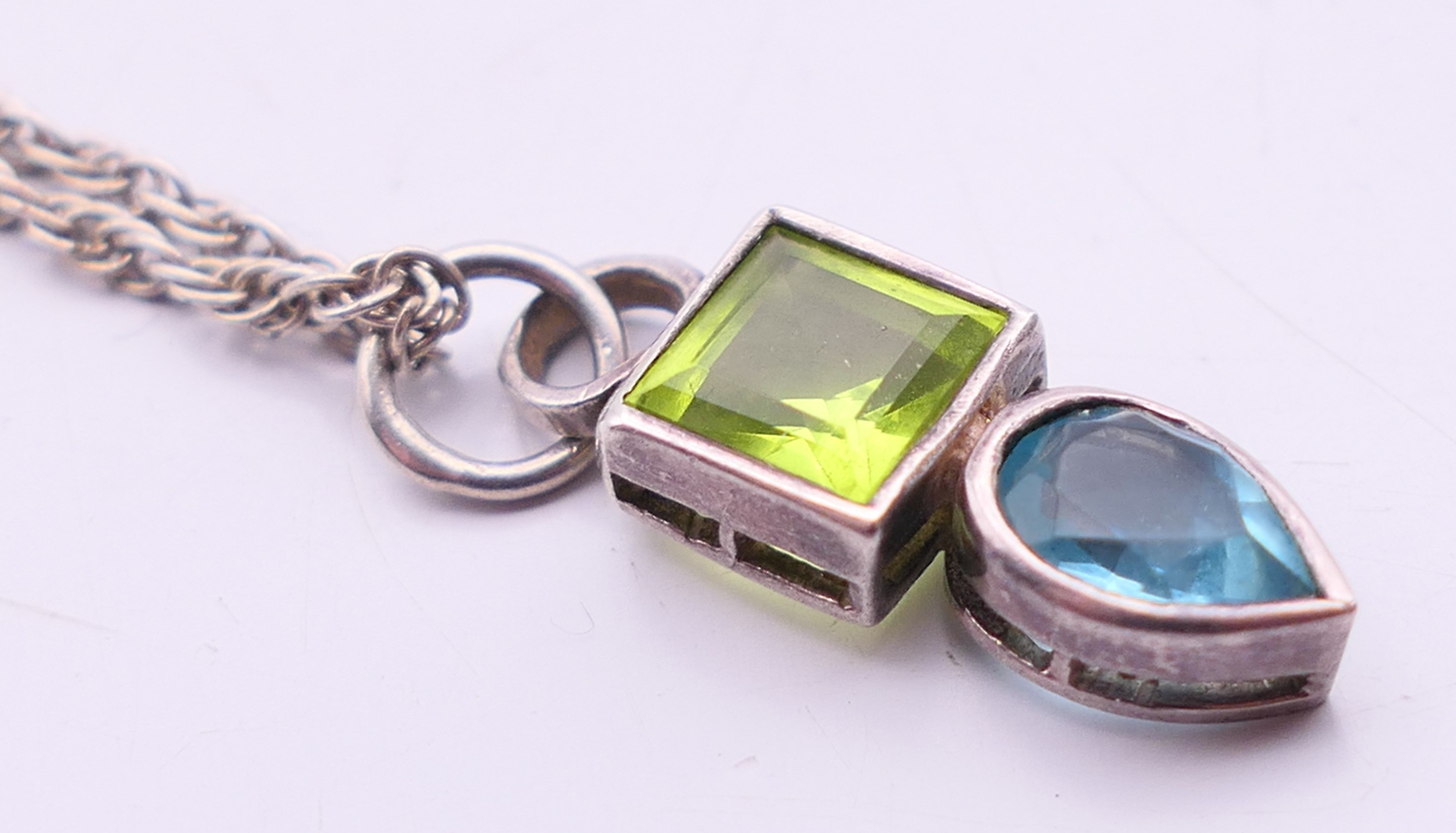 A silver peridot and blue topaz pendant and chain. Pendant 2 cm high, chain 40 cm long.