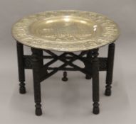 An Eastern brass-topped folding table. 75 cm diameter.