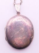 A silver locket and chain. The chain 58 cm long.