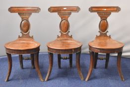 Three Georgian mahogany hall / footman's chairs with shaped seats, moulded splats and unusual