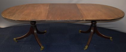 19th / 20thC twin pedestal mahogany dining table with removable central leaf, raised on brass