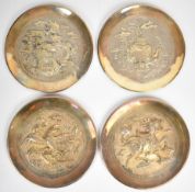 Four Chinese white metal chargers with decoration in relief, each 19.8cm in diameter.