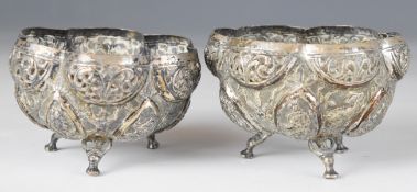 Pair of Indian white metal bowls with decoration in relief of deities, flora and fauna, raised on