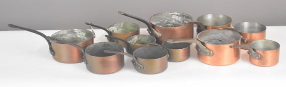 Three sets of copper saucepans comprising a set of five and two sets of three, length of largest