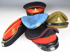 Five military hats comprising two for the Royal Artillery with badges, a Royal Artillery side hat