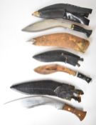 Three kukri knives, all with scabbards, two with kardas and chakmaks, together with a wooden