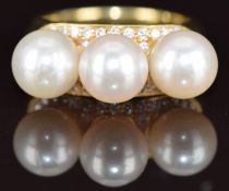 An 18ct gold ring set with three cultured pearls, each approximately 8mm, surrounded by diamonds,