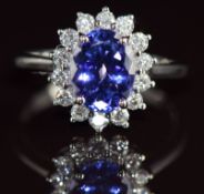 A platinum ring set with an oval cut tanzanite of approximately 2.1ct surrounded by diamonds, the