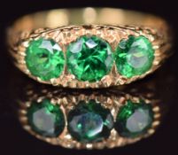 An 18ct gold ring set with three round cut tsavorites, 6.6g, size O
