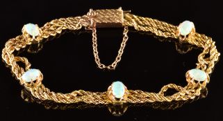 A c1910 9ct gold three strand rope twist bracelet set with five oval opal cabochons, 9.4g, 17cm