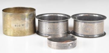 Three various hallmarked silver napkin rings including a pair of engine turned examples, together
