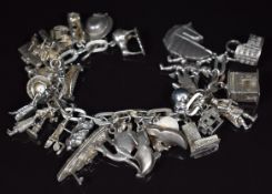 A silver charm bracelet with over twenty eight silver / white metal charms including Koala-bear,