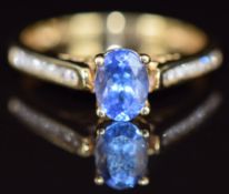 An 18k gold ring set with an oval cut tanzanite and diamonds to the shoulders, size O