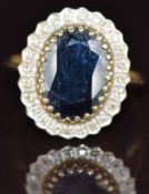 A 9ct gold ring set with an oval cut sapphire surrounded by diamonds, 4.4g, size T
