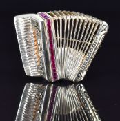 A 14k gold brooch in the form of an accordion set with synthetic calibre cut rubies and diamonds,