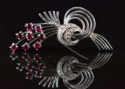 An 18ct white gold brooch in a stylised floral design set with eight round cut rubies, each