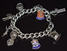 A silver charm bracelet with nine charms including drum by Nuno opening to reveal a trumpeter,