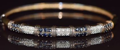A 9ct gold bangle set with sapphires and diamonds in seven panels, 11g, 6 x 5cm