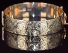A 9ct gold bangle with engraved scrolling decoration, 44.1g, 5.7 x 6cm