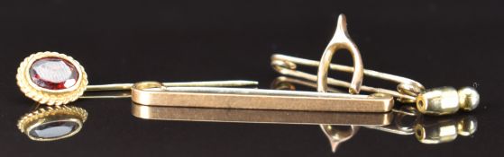 A 9ct gold brooch in the form of a wishbone, 9ct gold stick pin set with a garnet and a 9ct gold