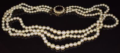 A three strand cultured pearl necklace, the 9ct gold clasp set with a garnet surrounded by