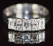 A 14k white gold ring set with three emerald cut diamonds of 0.4ct, 0.35ct and 0.35ct and four